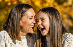 Mother and young daughter laughing together outdoors on an autumn day during flu season near Covington, LA