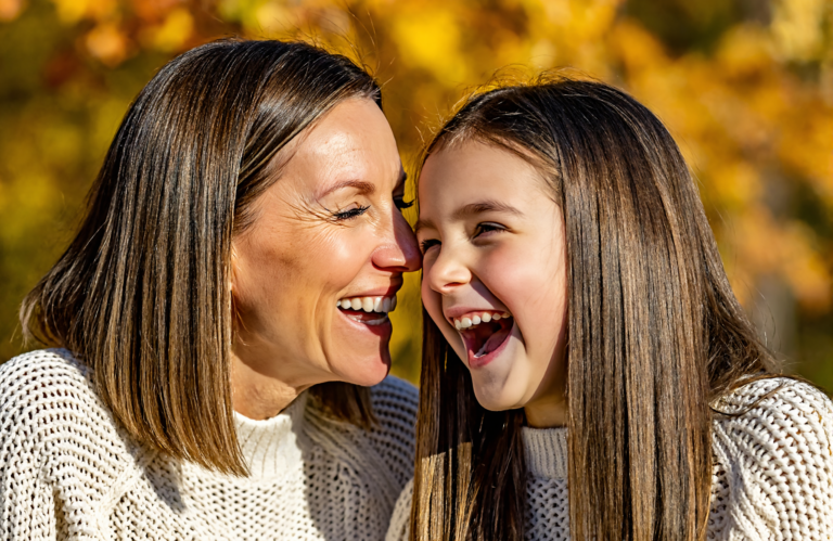 Mother and young daughter laughing together outdoors on an autumn day during flu season near Covington, LA