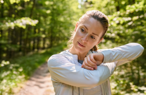 Woman on a sunny Northshore wooded trail checking her forearm for a poison ivy rash