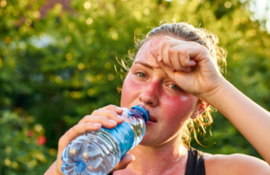 Overheated woman drinking water in a sunny backyard on a hot Louisiana day