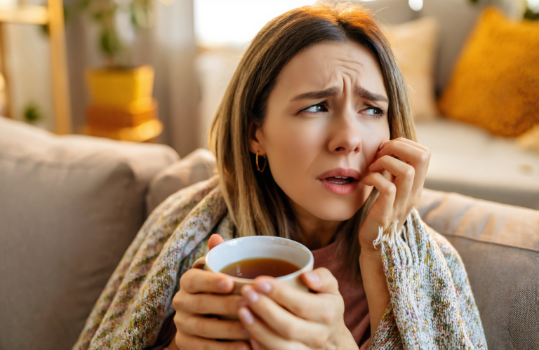 Woman with sinus infection symptoms resting at home with a warm mug of tea