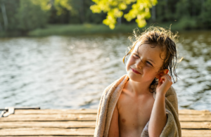 Young girl with a beach towel touching her sore ear after swimming at a Louisiana lake