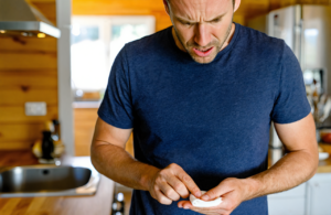 Man at a home kitchen counter pressing gauze to a cut finger before heading to urgent care in Covington, LA