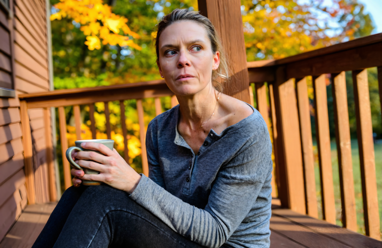 Woman resting on her front steps with a mug on a cool autumn morning while a lingering cough drags on near Covington, LA