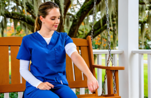 Woman in blue scrubs on a porch swing looking down at a bare forearm before a TB skin test in Covington, LA